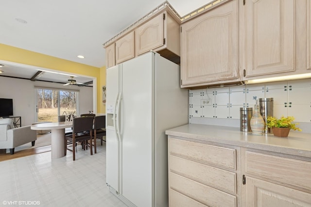 kitchen with light countertops, a ceiling fan, open floor plan, white refrigerator with ice dispenser, and light brown cabinetry