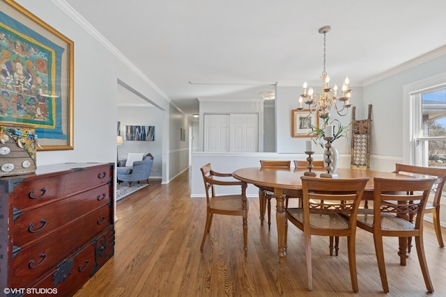dining space featuring baseboards, light wood-type flooring, crown molding, and a chandelier