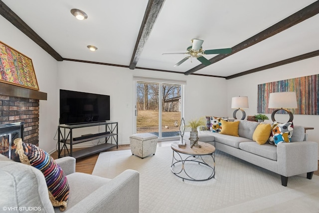 living area with ornamental molding, baseboards, beamed ceiling, ceiling fan, and wood finished floors