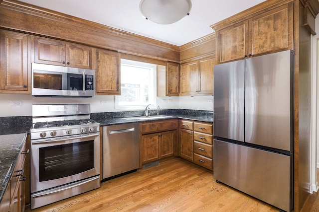 416 E Bauer Rd, Naperville, IL 60563 - kitchen with dark stone counters, a sink, stainless steel appliances, brown cabinetry, and light wood-type flooring