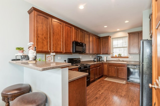 2835 Cattail Ct Unit B, Wauconda, IL 60084 - kitchen with black appliances, a peninsula, wood finished floors, a sink, and a breakfast bar area
