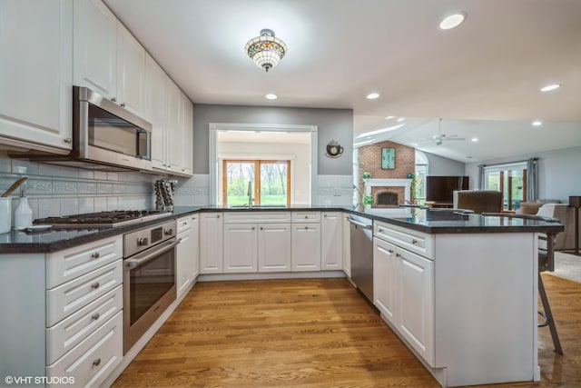 1485 Lexington Rd, Green Oaks, IL 60048 - kitchen featuring stainless steel appliances, open floor plan, vaulted ceiling, a peninsula, and a brick fireplace