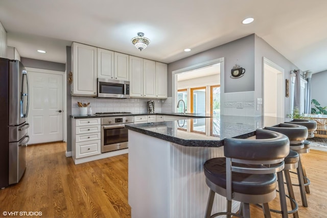 1485 Lexington Rd, Green Oaks, IL 60048 - kitchen featuring stainless steel appliances, a peninsula, a sink, a breakfast bar, and white cabinets
