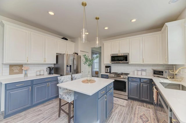 2034 Ingemunson Ln, Yorkville, IL 60560 - kitchen with stainless steel appliances, blue cabinetry, a sink, decorative backsplash, and light wood-style floors
