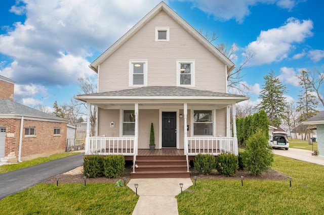american foursquare style home featuring a shingled roof, a porch, and a front yard
