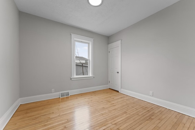 spare room featuring baseboards, visible vents, and light wood-style floors