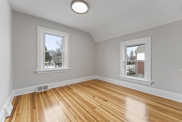 bonus room with baseboards, lofted ceiling, visible vents, and hardwood / wood-style flooring