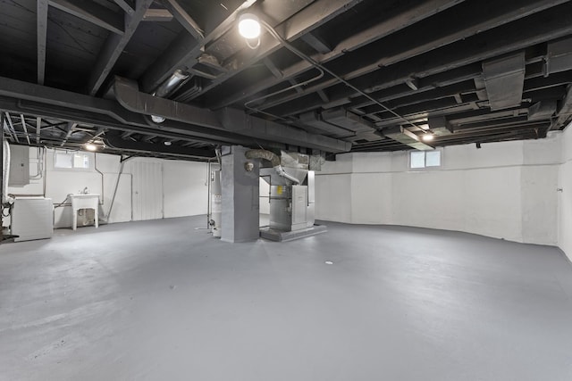 basement featuring water heater, a sink, washer / dryer, heating unit, and electric panel