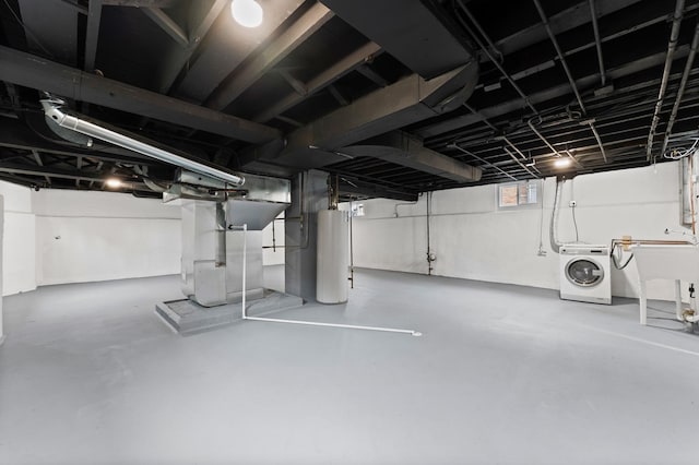 basement featuring heating unit, water heater, washer / clothes dryer, and a sink