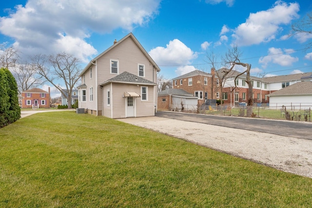 exterior space with a front lawn, a residential view, fence, and aphalt driveway