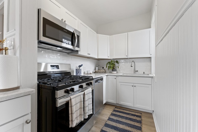 kitchen with white cabinetry, light wood-style floors, a sink, and stainless steel appliances