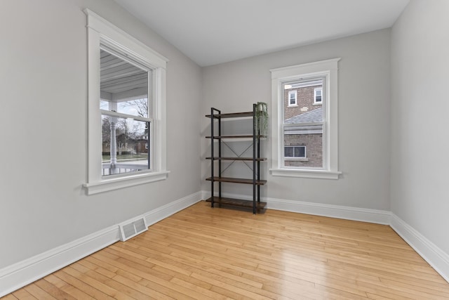 spare room with baseboards, visible vents, and hardwood / wood-style flooring