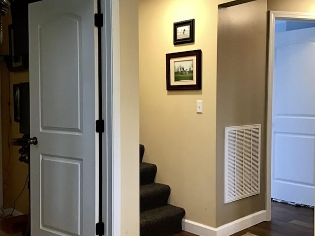 stairs with visible vents, baseboards, and wood finished floors