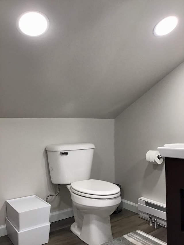 half bathroom featuring baseboards, baseboard heating, toilet, and wood finished floors