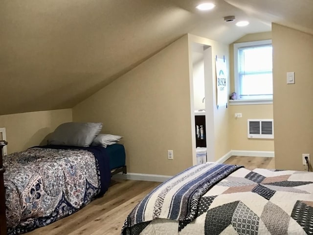 bedroom with visible vents, baseboards, lofted ceiling, and wood finished floors