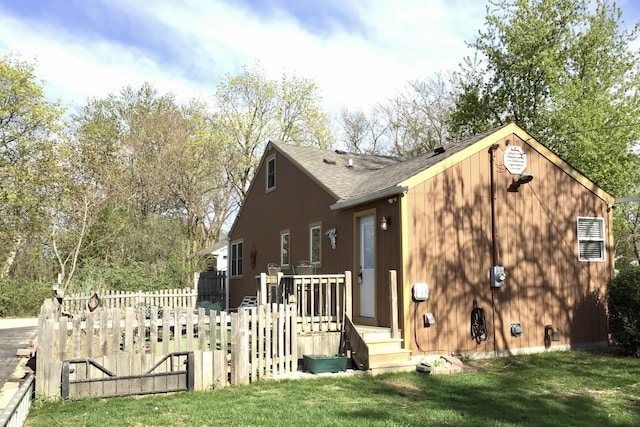 view of property exterior featuring fence, a shingled roof, and a yard