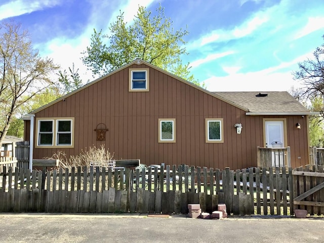 view of side of property with a shingled roof and a fenced front yard
