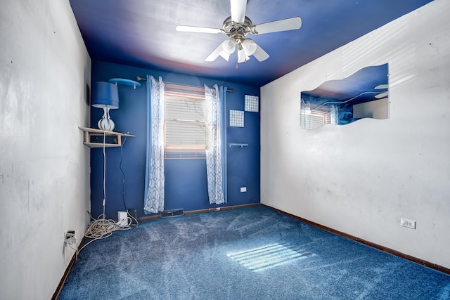 carpeted spare room with a ceiling fan and baseboards