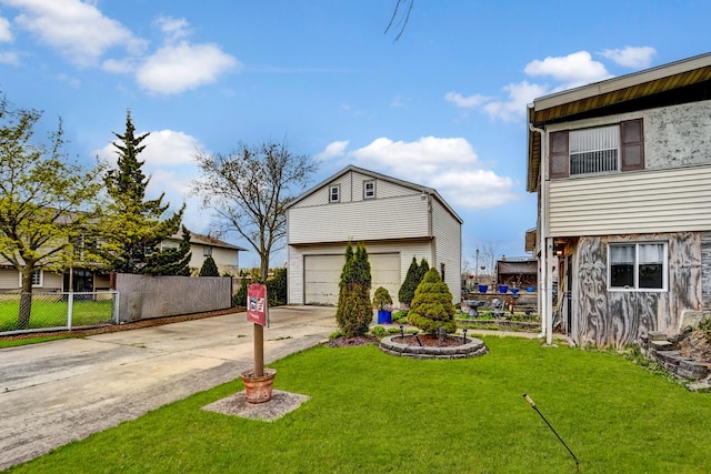 exterior space with concrete driveway, fence, a garage, an outdoor structure, and a yard