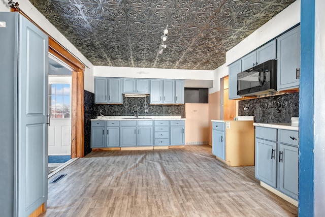 kitchen with black microwave, a sink, tasteful backsplash, and an ornate ceiling