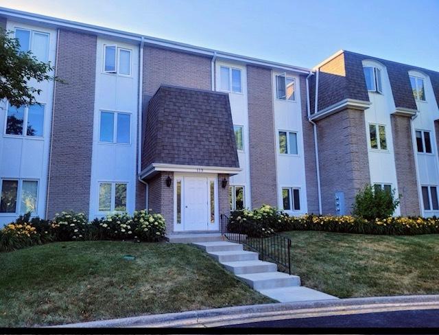 113 E Winchester Rd Unit C, Libertyville, IL 60048 - view of property featuring brick siding, roof with shingles, and a front yard