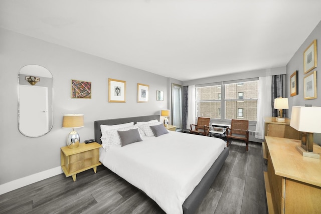 bedroom with dark wood-type flooring and baseboards