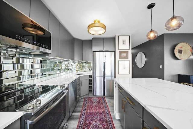 kitchen featuring pendant lighting, tasteful backsplash, wood finished floors, stainless steel appliances, and gray cabinetry