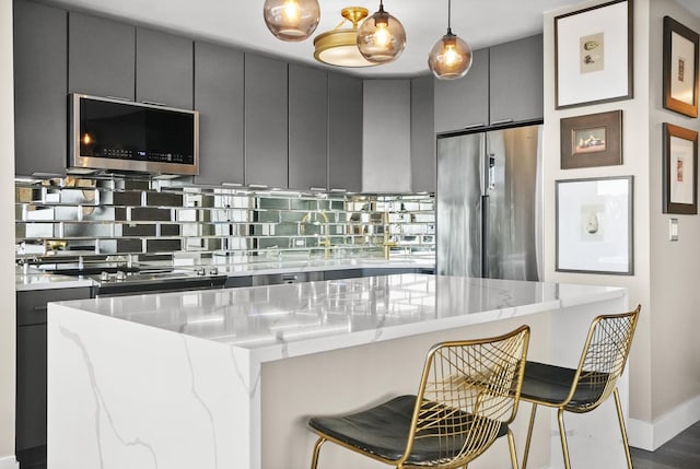 kitchen featuring a kitchen breakfast bar, stainless steel refrigerator, gray cabinets, a center island, and decorative backsplash