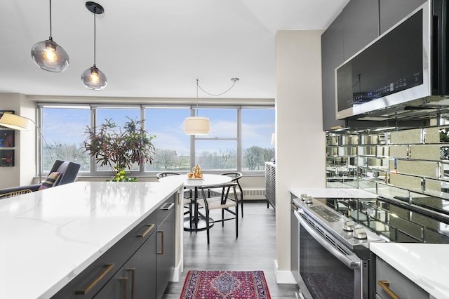 kitchen featuring plenty of natural light, pendant lighting, stainless steel range with electric cooktop, and wood finished floors