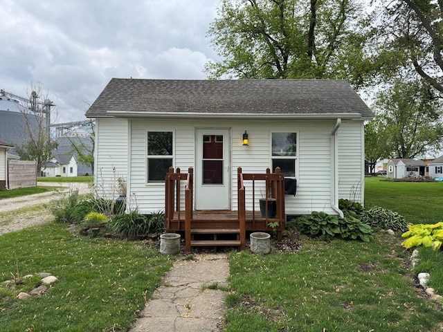 bungalow featuring a front lawn and roof with shingles