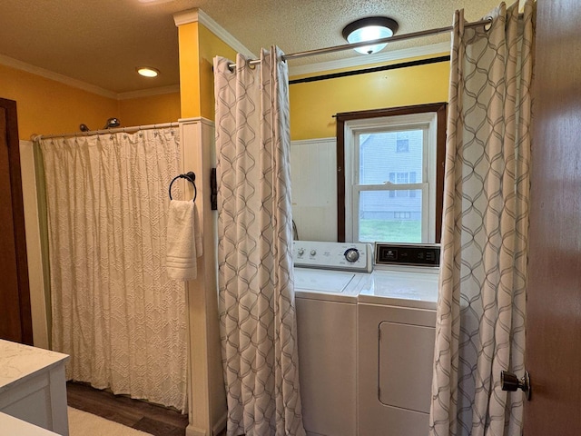 washroom featuring crown molding, wood finished floors, washer and dryer, a textured ceiling, and a wainscoted wall