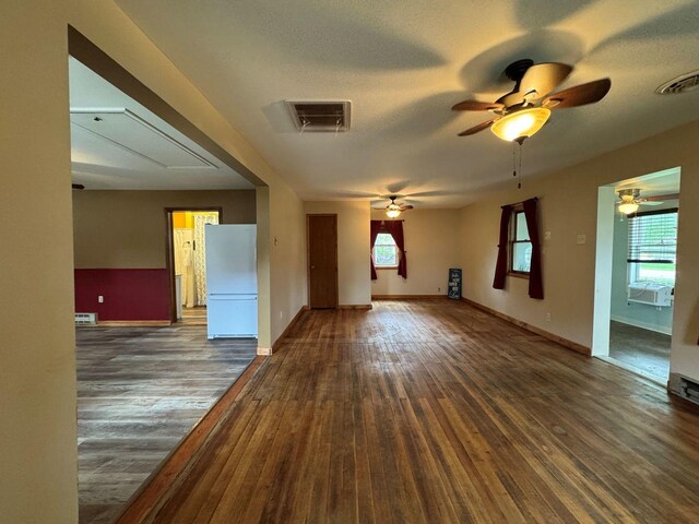 unfurnished living room with attic access, healthy amount of natural light, and ceiling fan