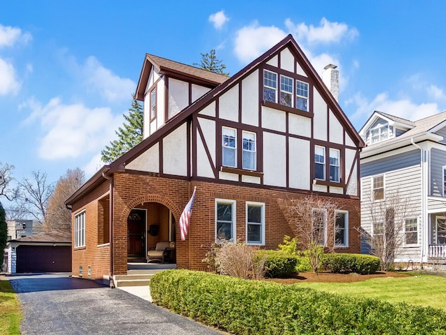 324 7th Ave, La Grange, IL 60525 - tudor-style house with stucco siding, an outdoor structure, a chimney, a porch, and brick siding