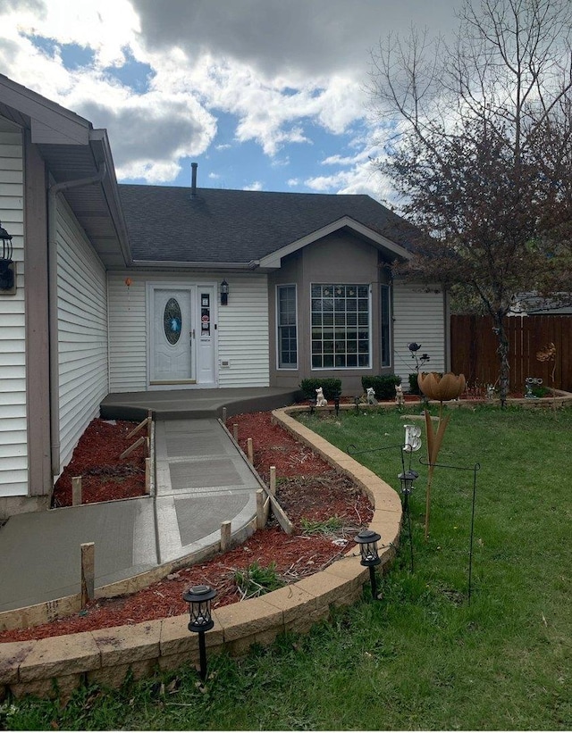view of front of home with fence, roof with shingles, and a front yard