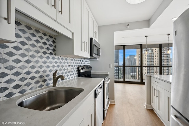 kitchen with backsplash, white cabinetry, appliances with stainless steel finishes, and a sink