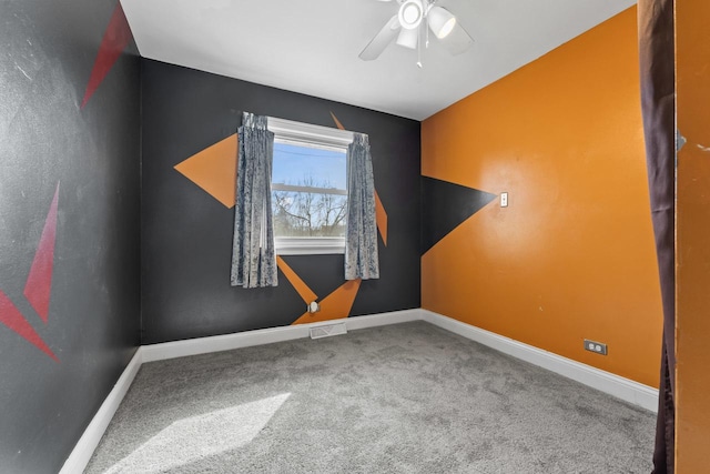 carpeted spare room with visible vents, baseboards, and a ceiling fan