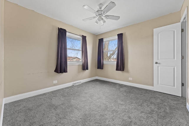 carpeted spare room featuring visible vents, baseboards, and ceiling fan