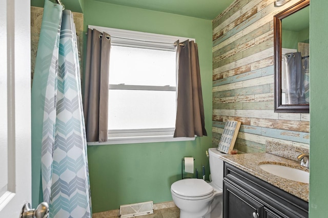 bathroom with toilet, vanity, wood walls, and visible vents