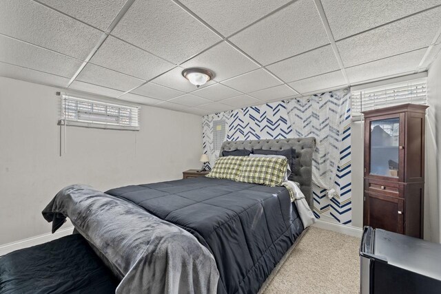 bedroom featuring an accent wall, a drop ceiling, baseboards, and carpet floors