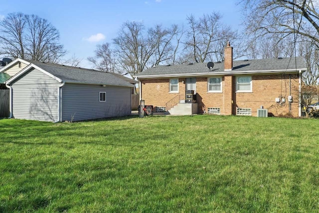 rear view of property featuring entry steps, a lawn, a chimney, an outdoor structure, and brick siding