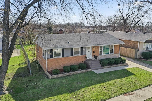 ranch-style home featuring brick siding, a front yard, fence, and a chimney