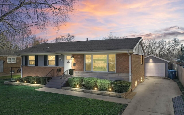 view of front of home with concrete driveway, a front lawn, brick siding, an outbuilding, and fence