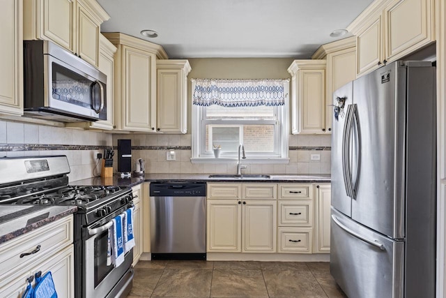 kitchen featuring a sink, tasteful backsplash, appliances with stainless steel finishes, and cream cabinets