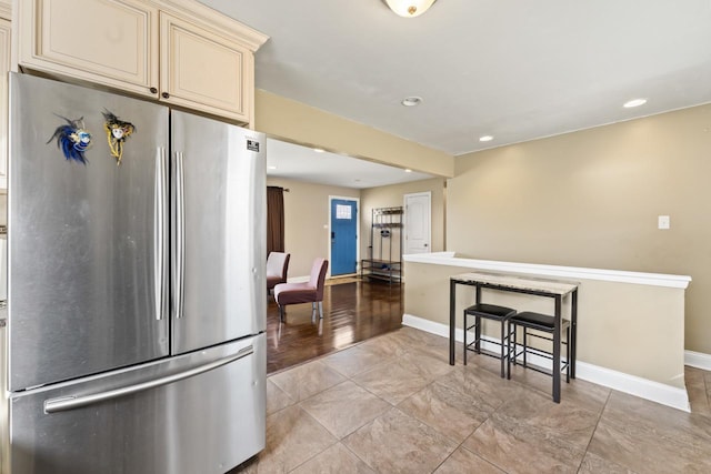 kitchen with recessed lighting, cream cabinets, baseboards, and freestanding refrigerator