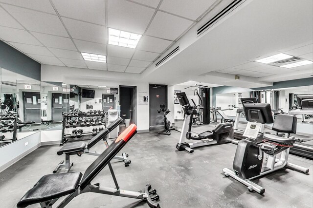 gym featuring visible vents, a paneled ceiling, and baseboards