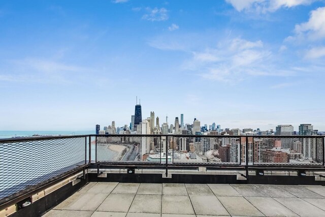 view of patio featuring a view of city, a water view, and a balcony