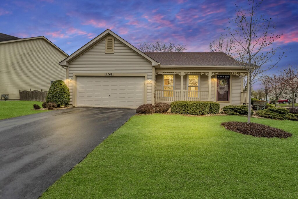 2769 Yosemite Dr, Aurora, IL 60503 - ranch-style home featuring a porch, an attached garage, a lawn, and aphalt driveway