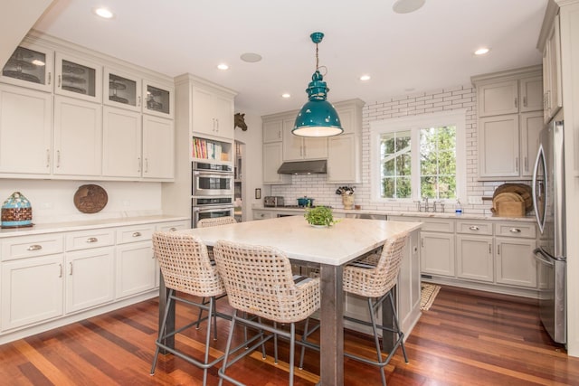 4529 Washington St, Downers Grove, IL 60515 - kitchen featuring tasteful backsplash, dark wood-style flooring, under cabinet range hood, a breakfast bar area, and stainless steel appliances