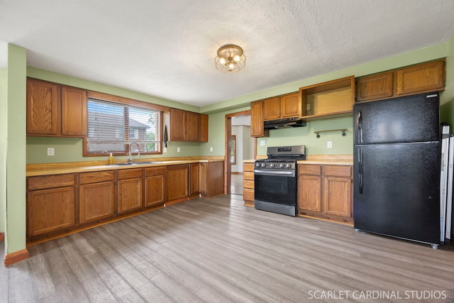 301 S Shabbona Rd, Shabbona, IL 60550 - kitchen featuring freestanding refrigerator, stainless steel gas stove, a sink, under cabinet range hood, and light countertops