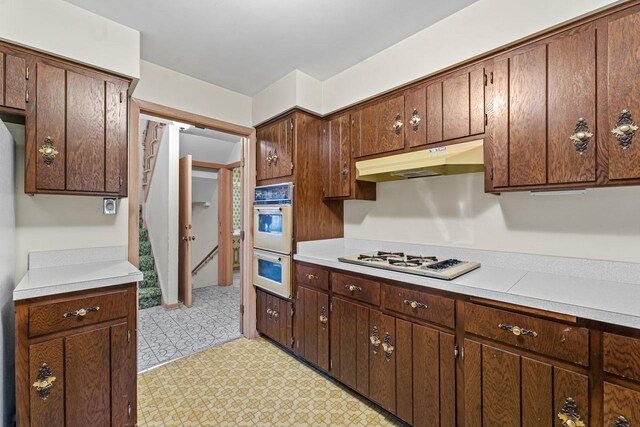 7415 W Ute Ln, Palos Heights, IL 60463 - kitchen featuring white appliances, under cabinet range hood, light countertops, light flooring, and dark brown cabinetry
